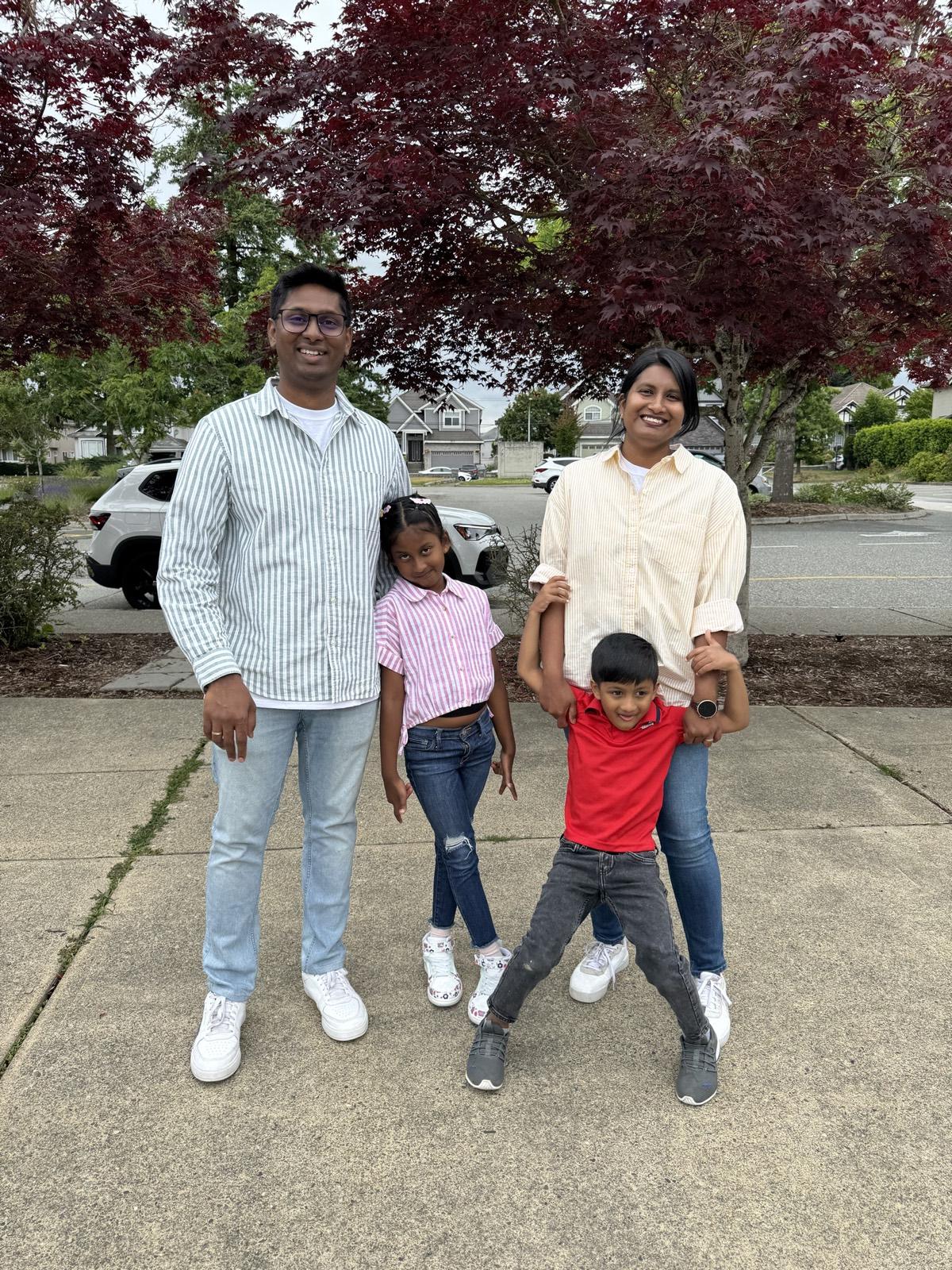 Fredrick with his wife and their two children on a neighbourhood street under a Japanese maple.